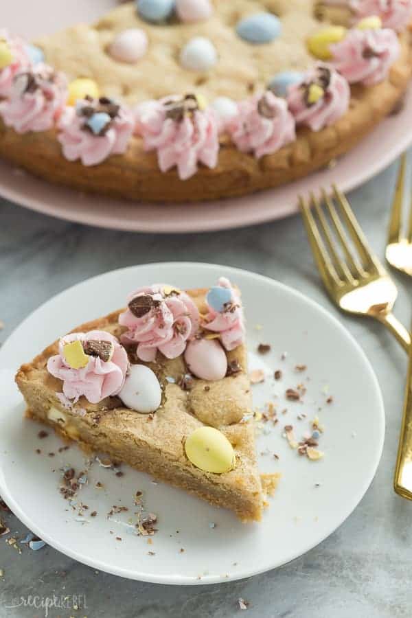 easter mini egg cookie cake slice on white plate with whole cookie cake in the background