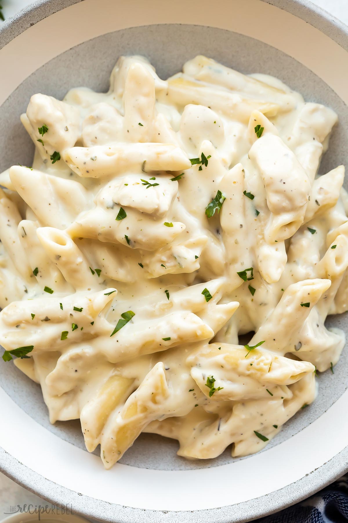 close up image of chicken alfredo pasta in grey bowl.