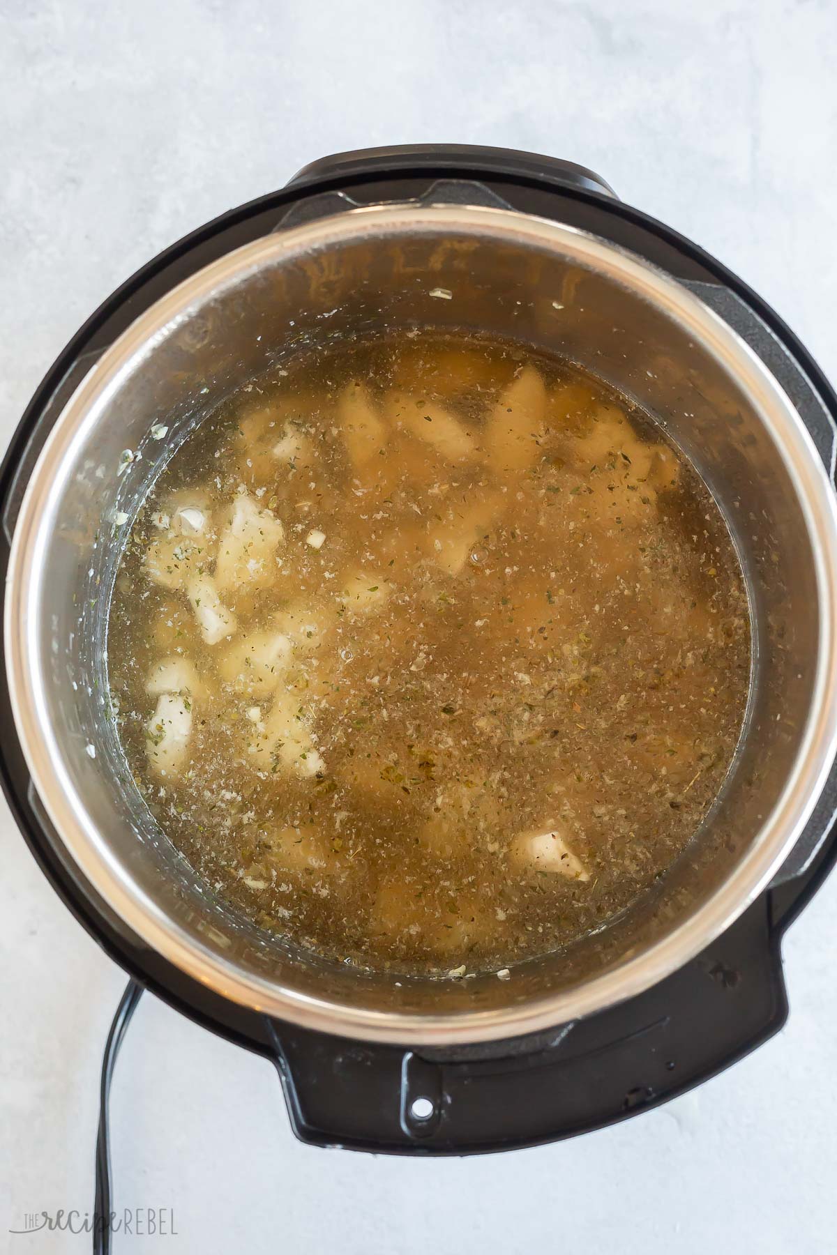 broth added to chicken pieces in pressure cooker.