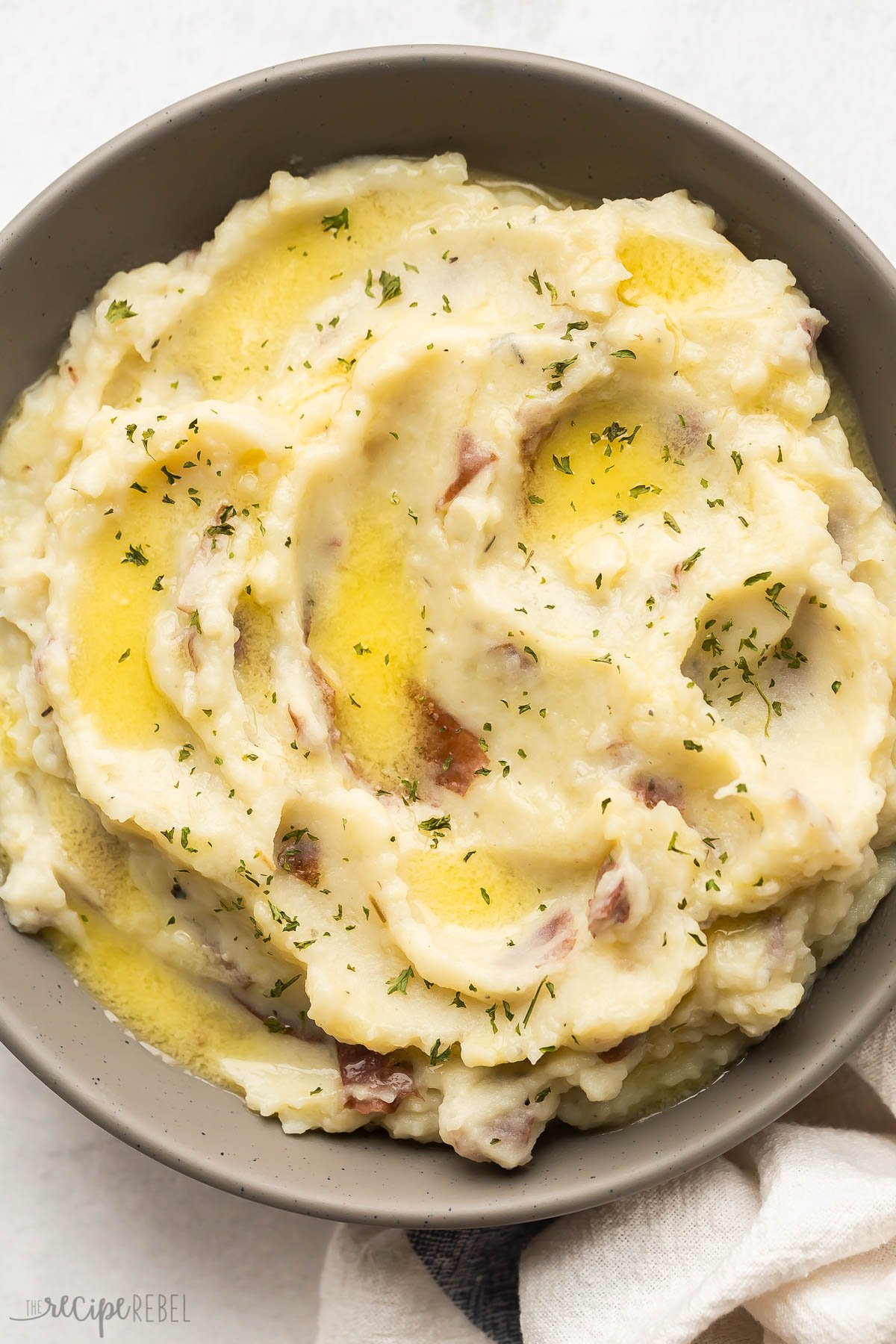 overhead image of mashed potatoes with melted butter in grey bowl.