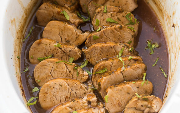 square image of slow cooker pork tenderloin sliced in sauce