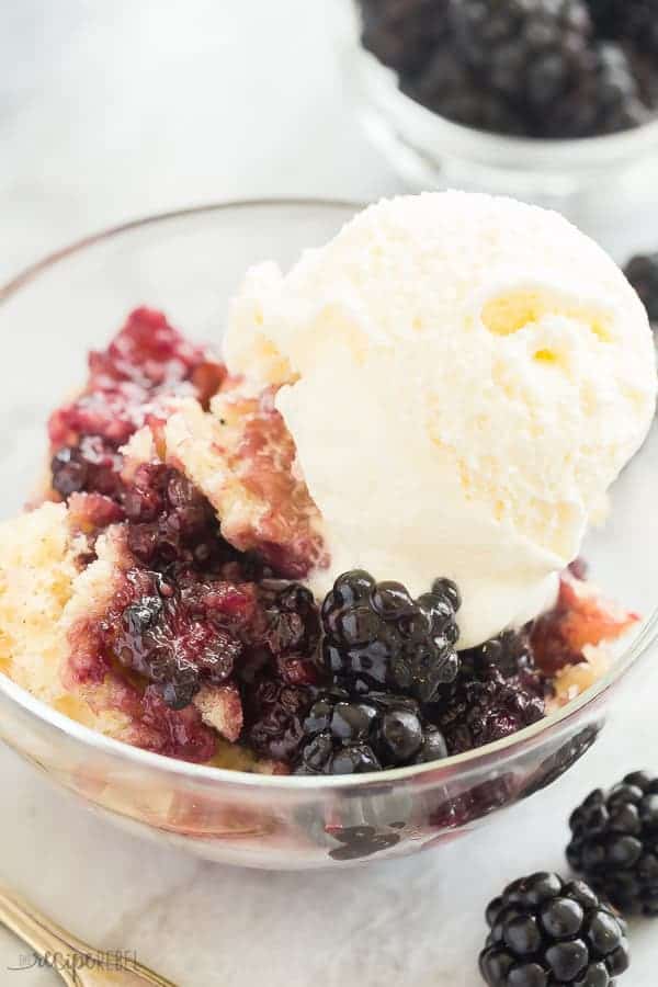 blackberry cobbler in glass bowl with scoop of vanilla ice cream