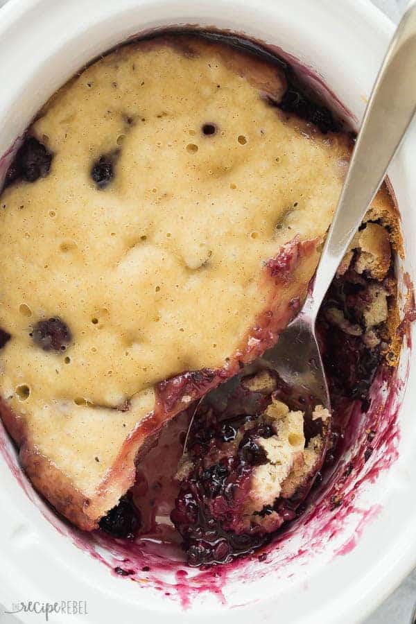 This Easy Crockpot Blackberry Cobbler recipe is a winner for sure! It comes together with just 10 minutes prep and cooks in the slow cooker, keeping your house cool and your oven free! Loaded with fresh blackberries and a crisp, cakey topping. Just begging for a scoop of vanilla ice cream! #slowcooker #crockpot #dessert #blackberry #recipe crockpot blackberry cobbler overhead in slow cooker with metal spoon
