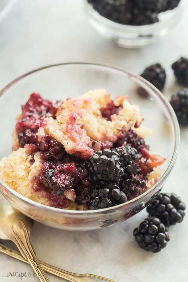 blackberry cobbler in a glass bowl with fresh blackberries on the side