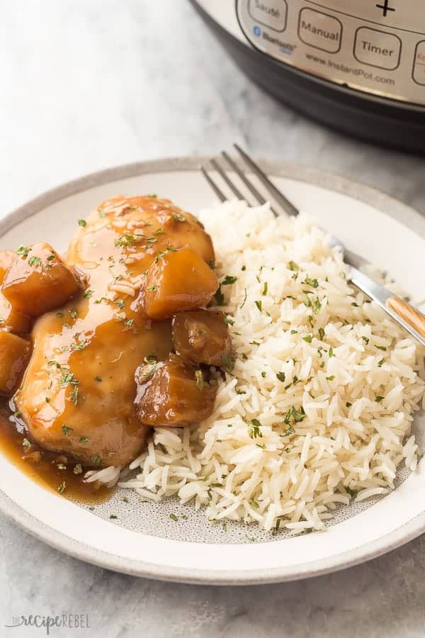 instant pot pineapple chicken breasts with rice on grey plate with pressure cooker in the background