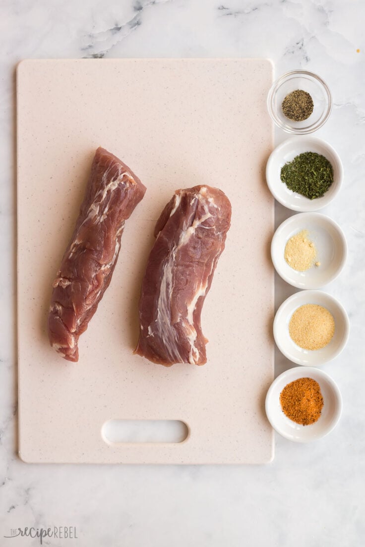 pork tenderloin cut in half with seasonings beside in bowls