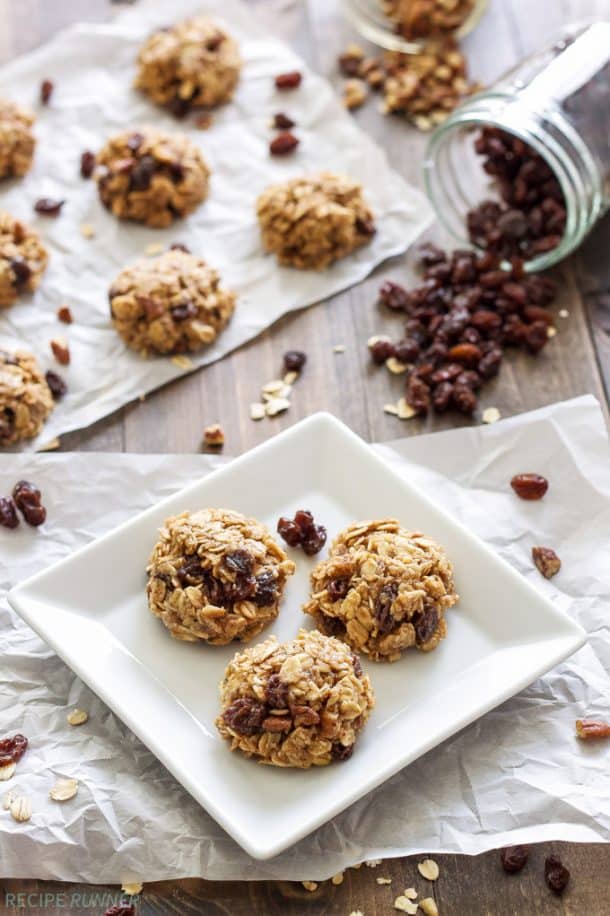 no bake oatmeal raisin cookies on a white plate with raisins spilling out from jar