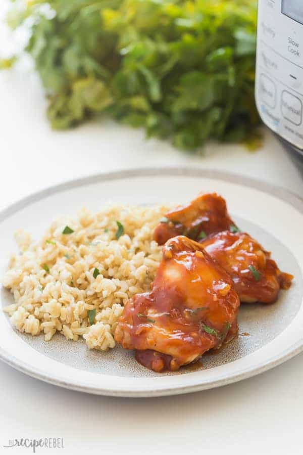 pressure cooker chicken thighs in bbq sauce on grey plate with rice and parsley in background