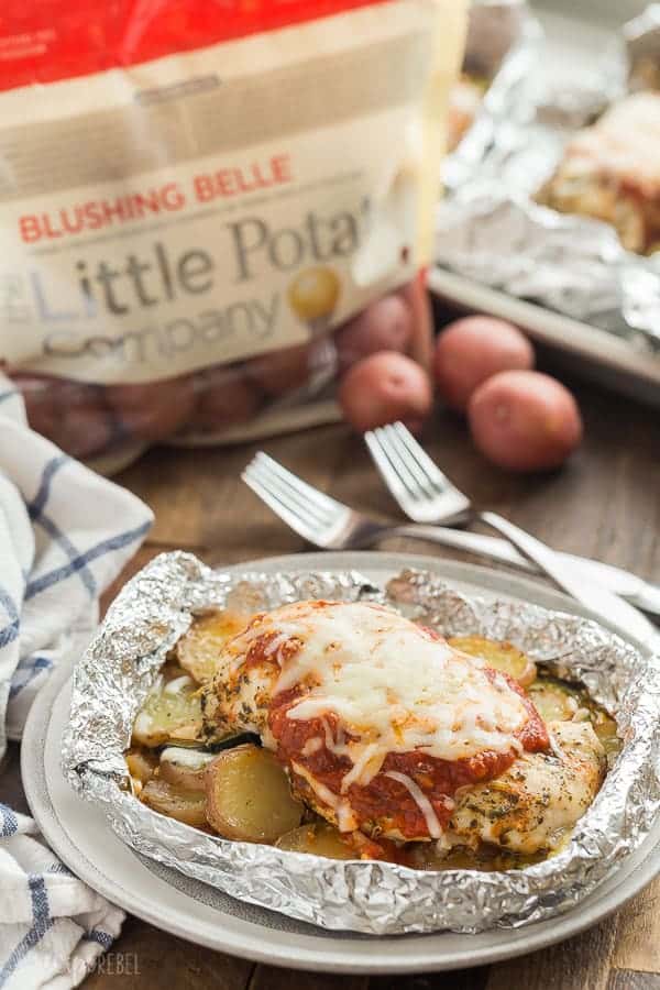 chicken parmesan foil packets on plate with bag of little potatoes in the background