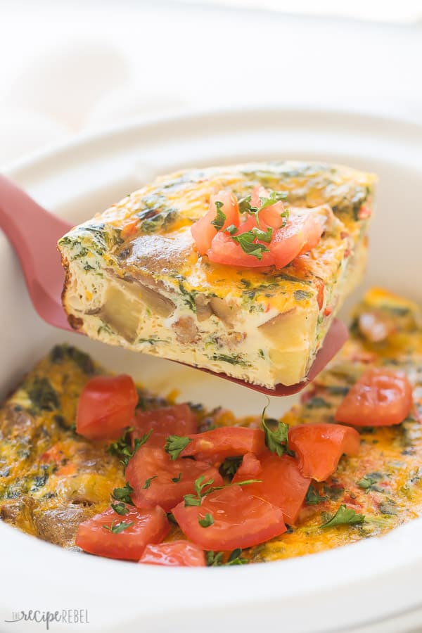 triangle slice of breakfast casserole being pulled out of crockpot on a red spatula