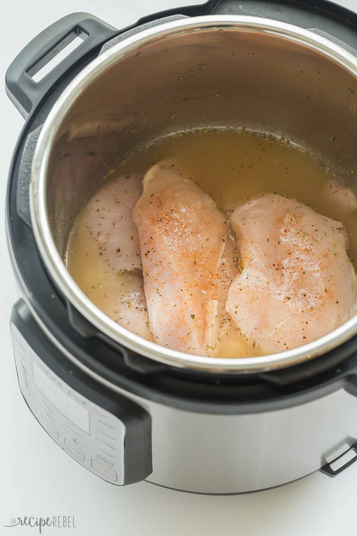 four chicken breasts in instant pot with seasoning ready to cook.