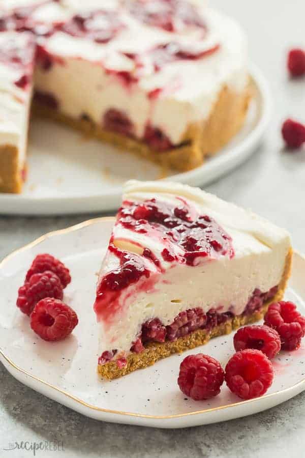 white chocolate raspberry cheesecake on white plate with fresh raspberries