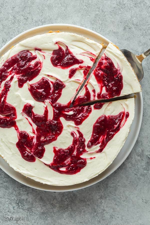 white chocolate cheesecake with raspberry swirls overhead on grey background