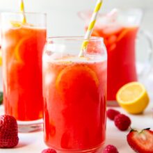 two glasses of pink lemonade and a pitcher in the background