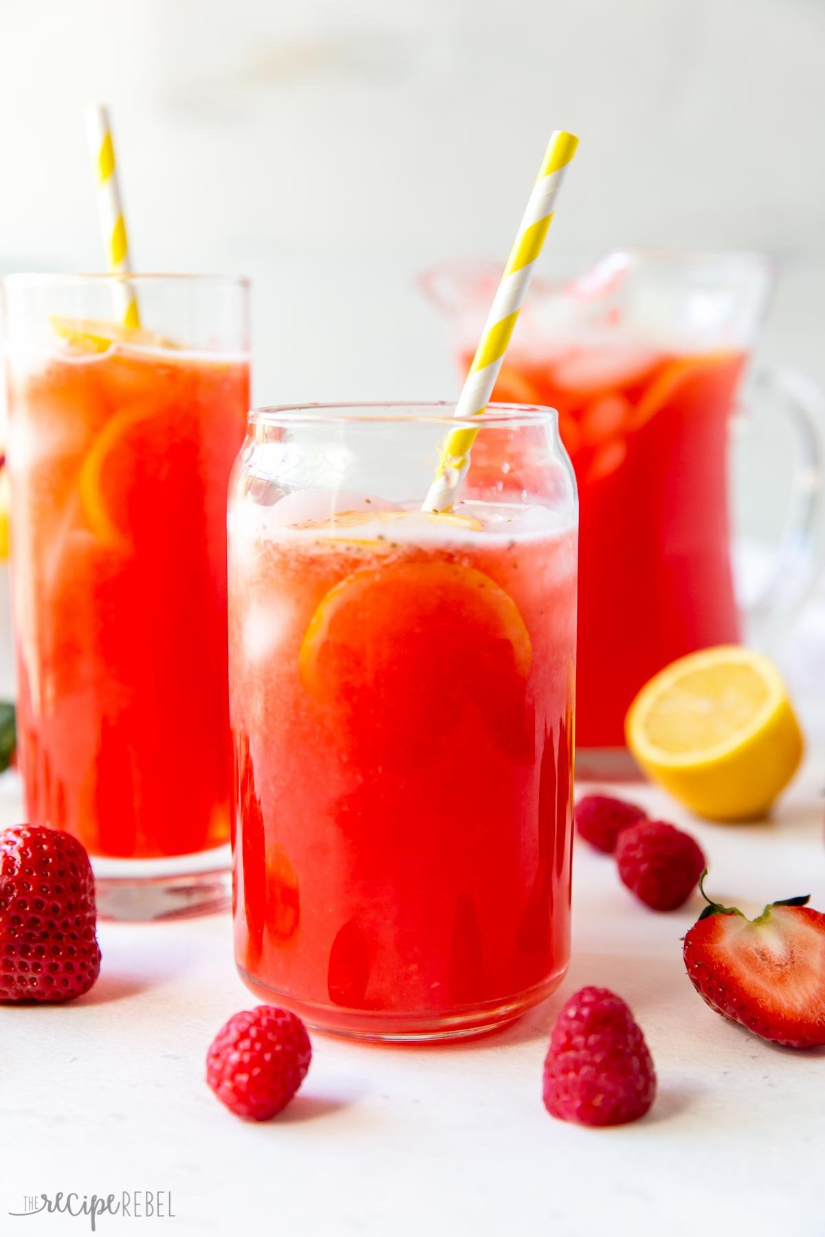 two glasses of pink lemonade and a pitcher in the background