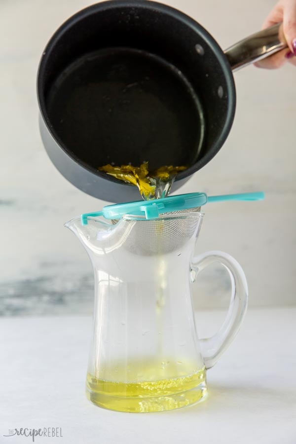 straining lemon simple syrup over pitcher