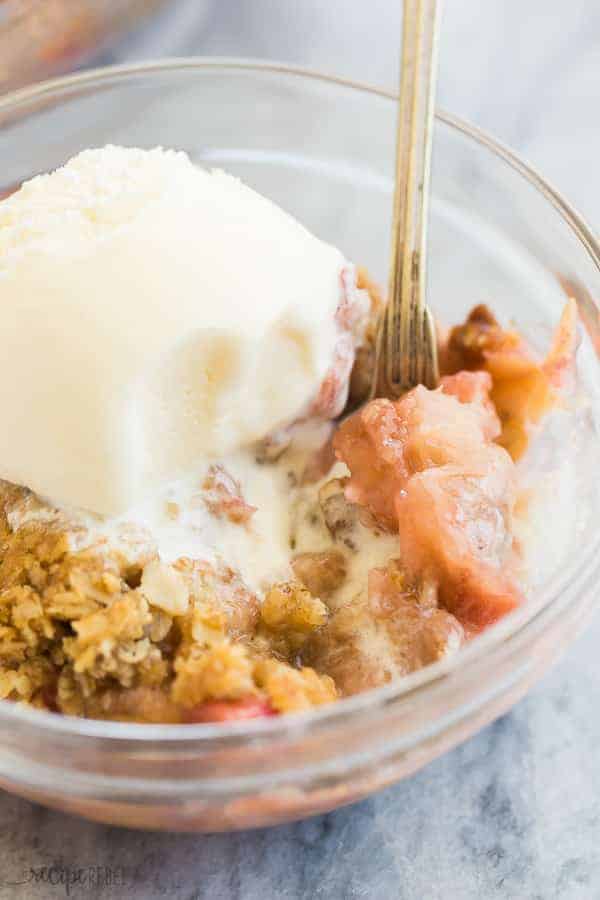 rhubarb crisp in a clear glass bowl with scoop of ice cream
