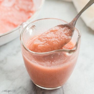 a spoon scooping rhubarb sauce out of a glass cup.