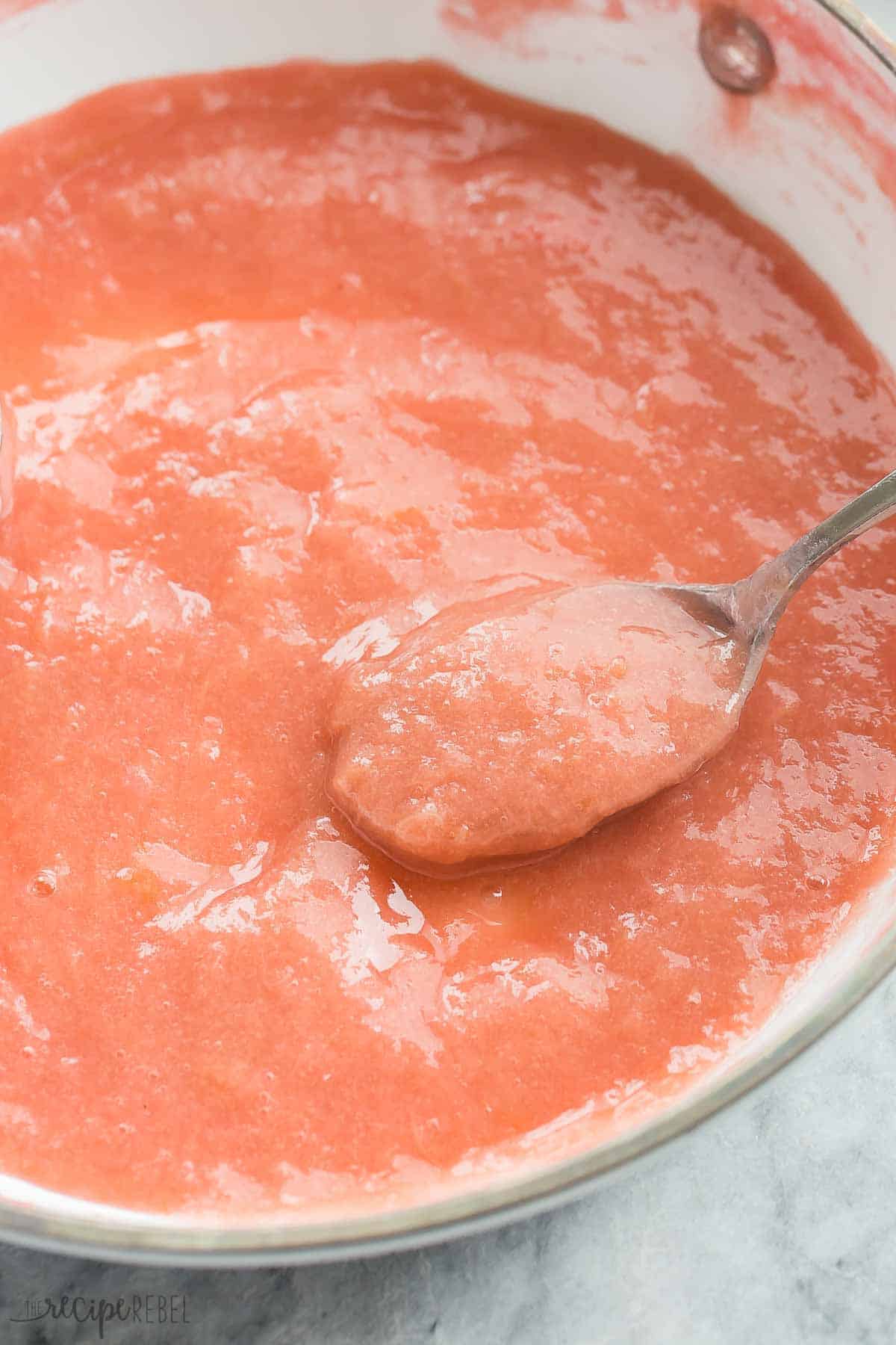 This Rhubarb Sauce Recipe is a quick, easy way to make the most of that Spring rhubarb! It's tart and sweet and perfect over ice cream, cake, vanilla yogurt or pancakes for breakfast. Includes variations: strawberry rhubarb sauce, blueberry, and more. With step by step RECIPE VIDEO you can follow along. #rhubarb #sauce #condiments #recipe #recipes #homemade #easyrecipe #spring #summer | rhubarb recipes | ice cream toppings | fruit sauce recipes | spring dessert spoon scooping rhubarb sauce out of a white skillet.