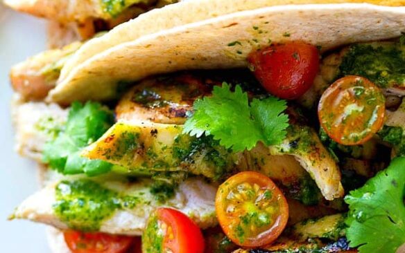 greek marinated chicken tacos with cilantro and tomatoes.