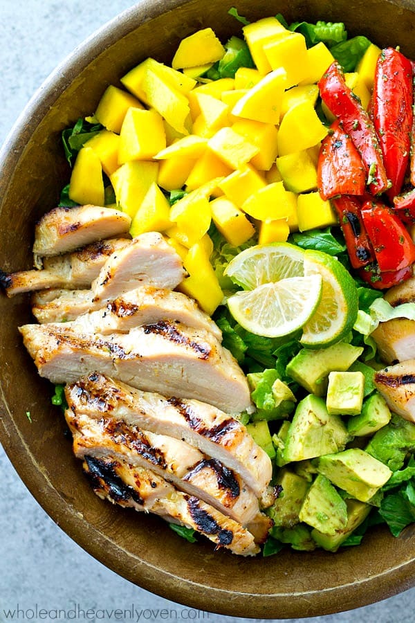 hawaiian grilled chicken mango salad overhead with fresh mango chunks roasted red peppers avocado and lime wedges