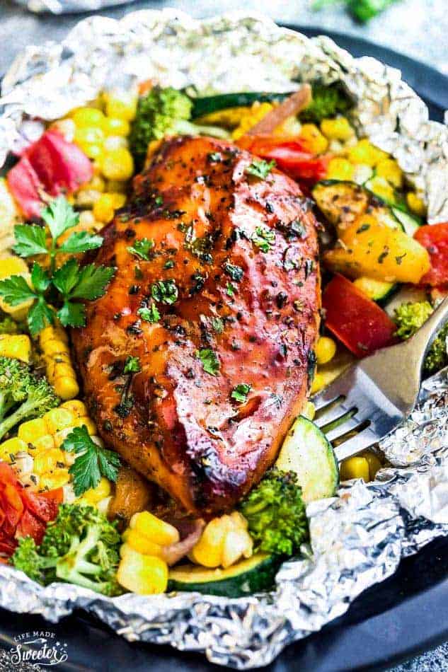 barbecue chicken foil packets with vegetables and fork stuck in vegetables