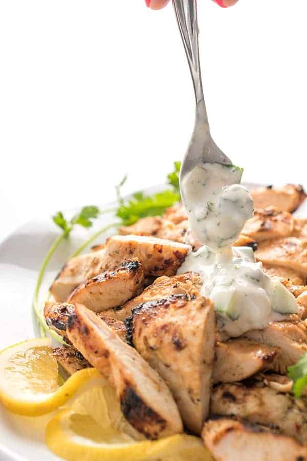 tandoori grilled chicken being drizzle with creamy sauce on a spoon