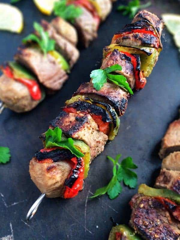 greek beef souvlaki skewers with peppers on black background