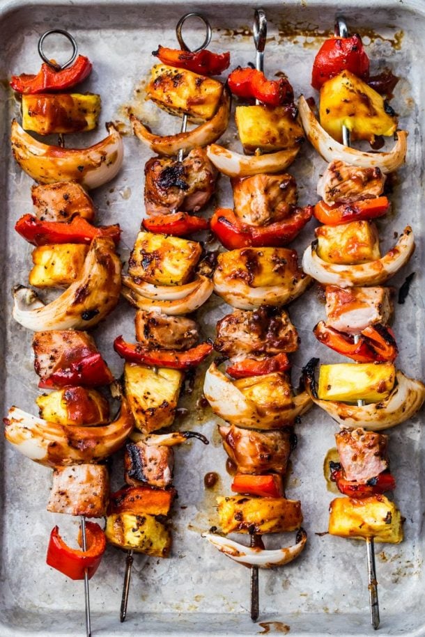 sweet and tangy pork kabobs on metal skewers on a rimmed baking sheet