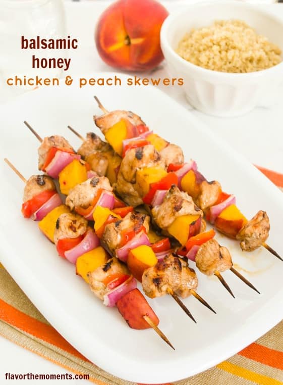 balsamic honey chicken peach skewers on a white plate with whole peach in the background