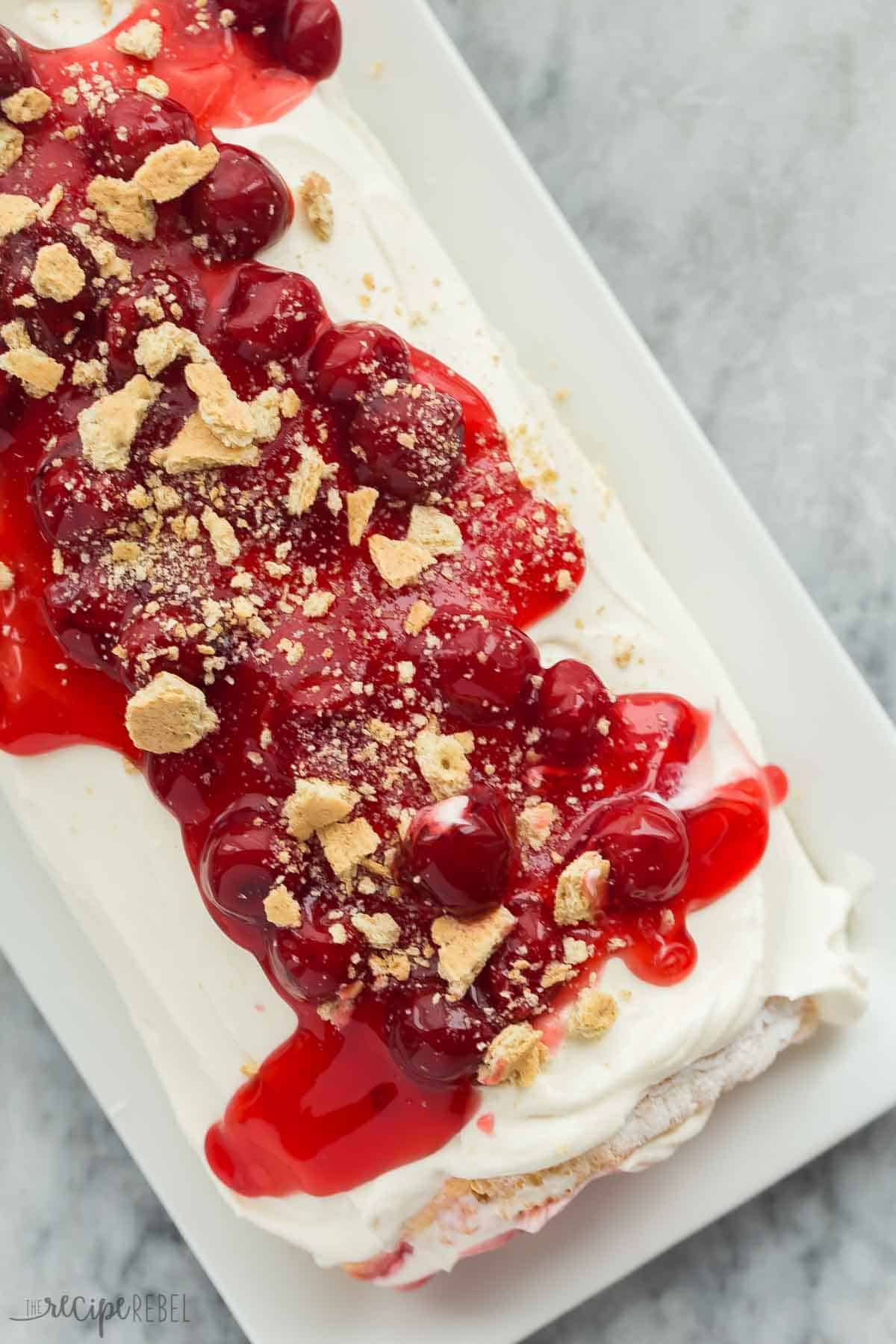 cherry cheesecake cake roll overhead on white plate on grey marble background