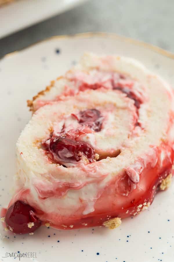 cherry cheesecake angel food cake roll slice on white speckled plate