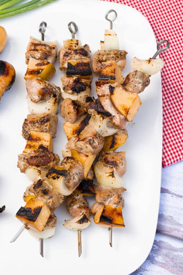 All kinds of kabob recipes for summer grilling! Chicken kabobs, shrimp kabobs, steak kabobs, and dessert kabobs! Because food on a stick is more fun ;) pork apple kebabs on white plate on top of a red checked napkin
