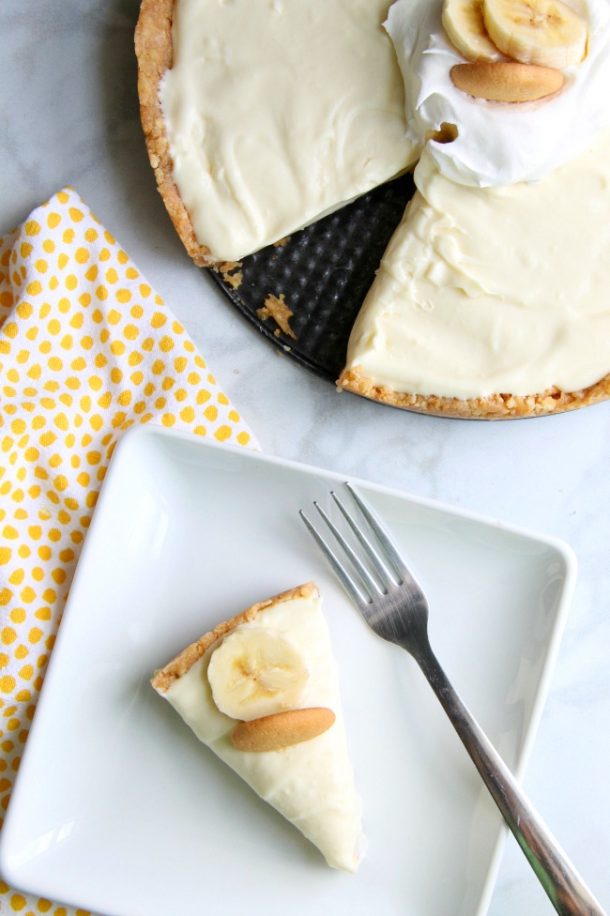 banana pudding no bake cheesecake slice on white plate with banana slice and nilla wafer