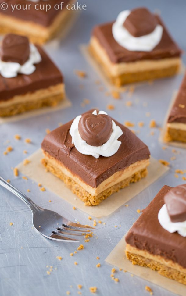 chocolate peanut butter cheesecake bars with whipped cream and a chocolate heart on top