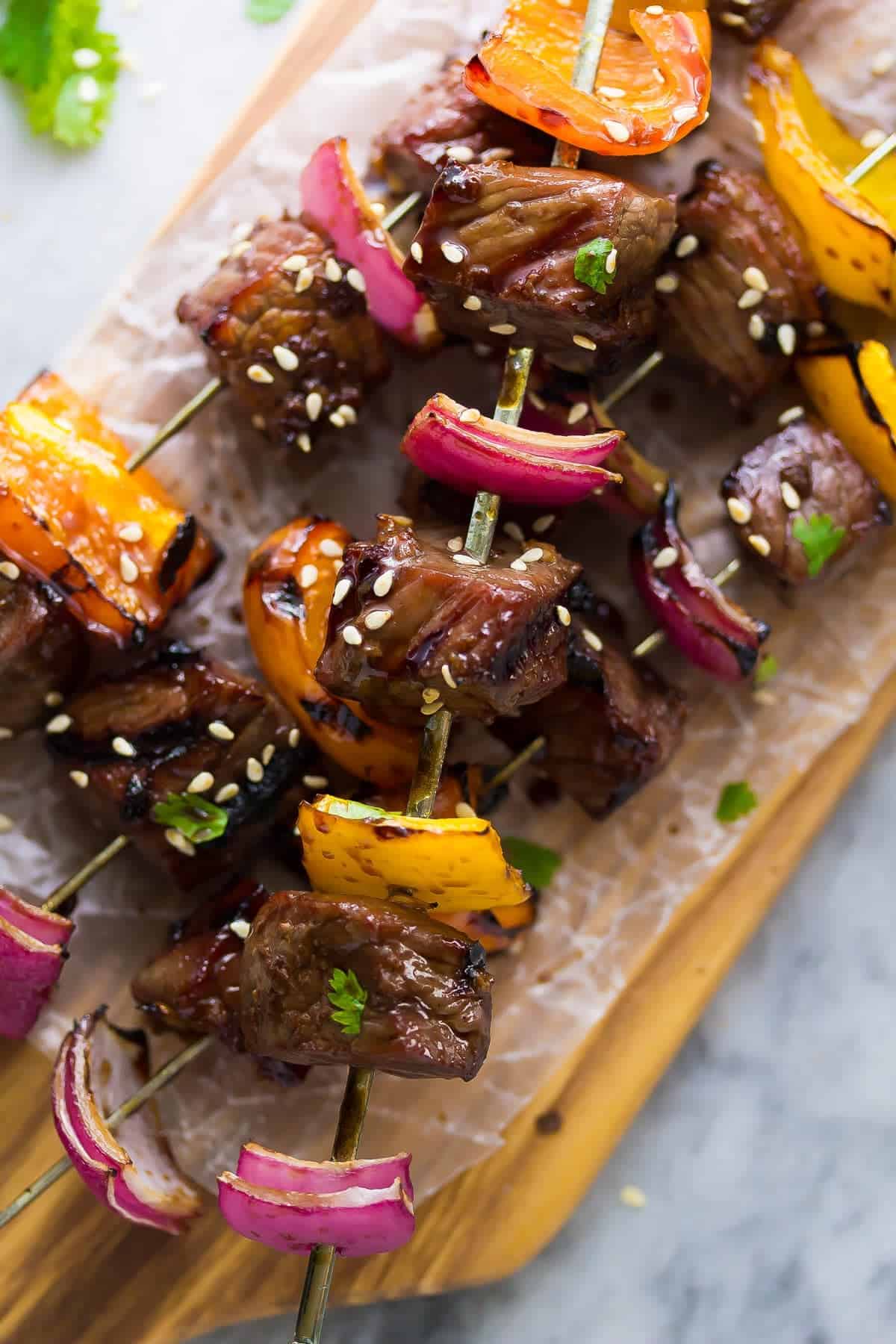 All kinds of kabob recipes for summer grilling! Chicken kabobs, shrimp kabobs, steak kabobs, and dessert kabobs! Because food on a stick is more fun ;) korean beef skewers close up with peppers and red onions and sprinkled with sesame seeds