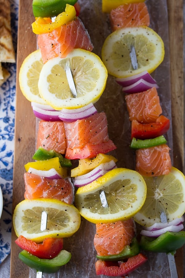 All kinds of kabob recipes for summer grilling! Chicken kabobs, shrimp kabobs, steak kabobs, and dessert kabobs! Because food on a stick is more fun ;) souvlaki salmon kabobs close up with fresh lemon slices uncooked