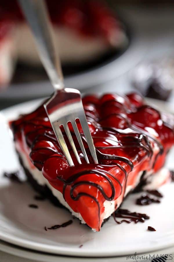 no bake cherry cheesecake with chocolate drizzle and fork poking into cheesecake
