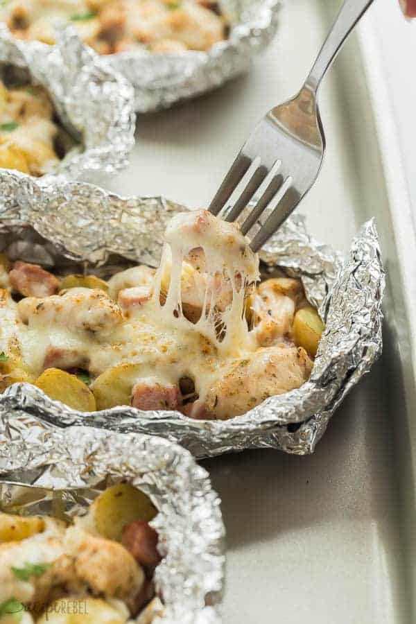 chicken cordon bleu foil packs up close with fork pulling out a cheesy potato
