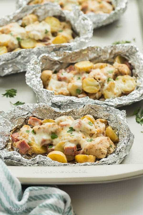 chicken cordon bleu foil packs with ham chunks chicken breast potatoes and cheese on a sheet pan