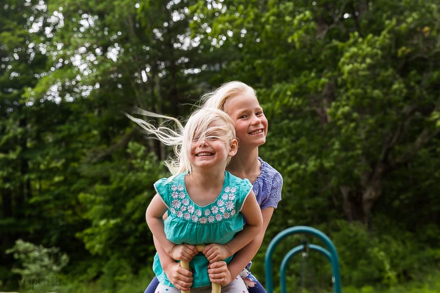 two kids on a seaswa with trees in the background