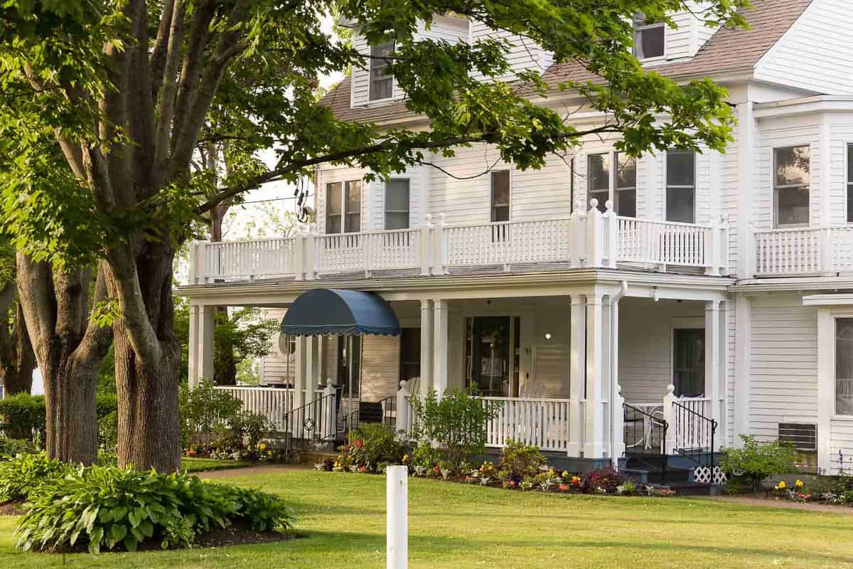 old house in ogunquit maine with large trees in front