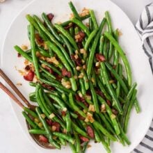 overhead image of green beans with bacon on white serving platter