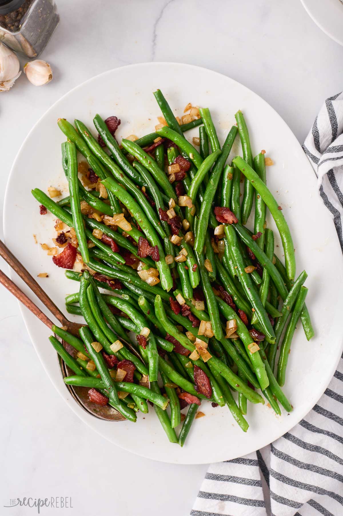 overhead image of green beans with bacon on white serving platter