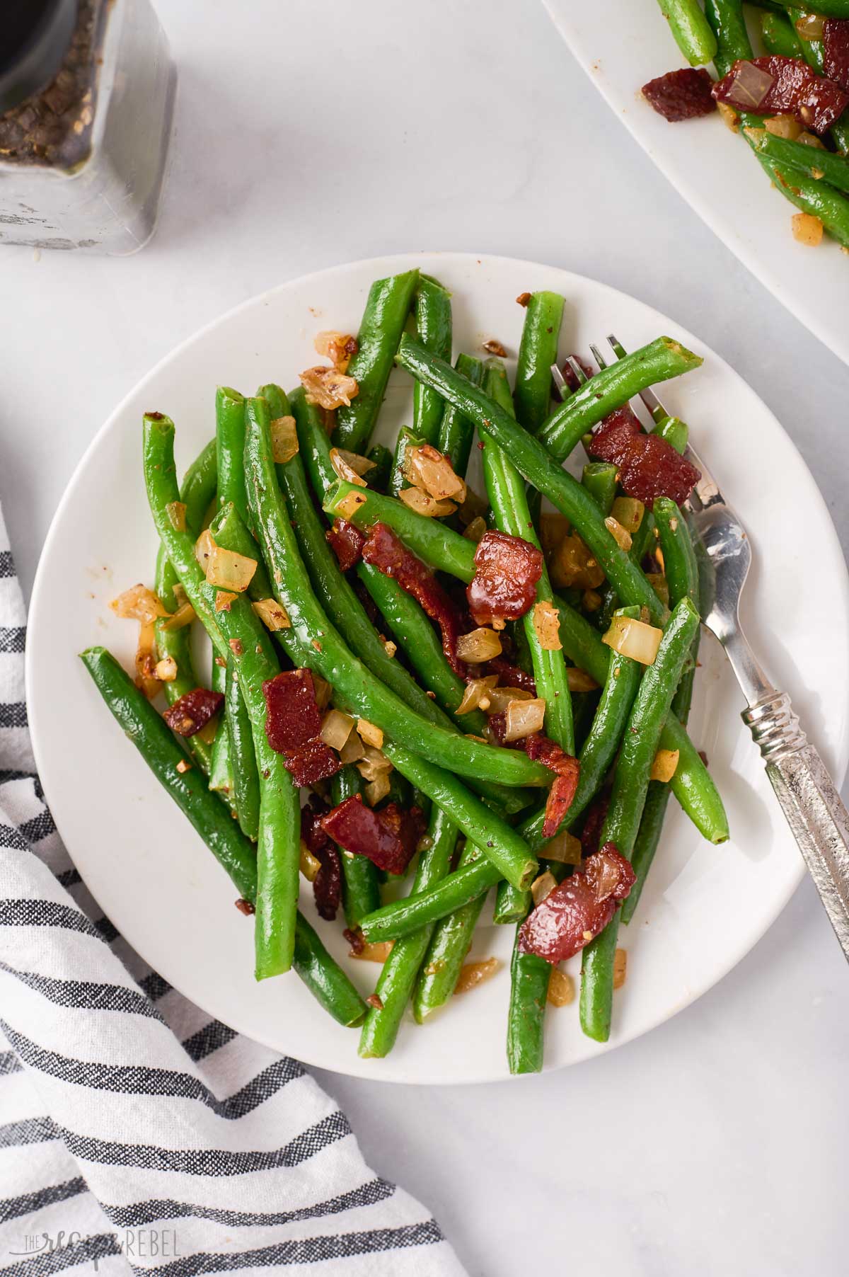 overhead image of green beans with bacon on white plate