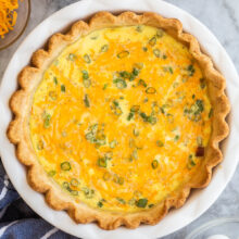 overhead image of whole ham quiche on marble background