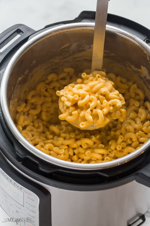 This is the CREAMIEST Instant Pot Mac and Cheese -- it's loaded with cheese and comes together so quickly! The perfect Instant Pot pasta recipe, great for customizing to your family's tastes with added protein or veggies. #macaroni #cheese #pasta #dinner #instantpot #pressurecooker instant pot mac and cheese in pressure cooker with scoop being pulled out