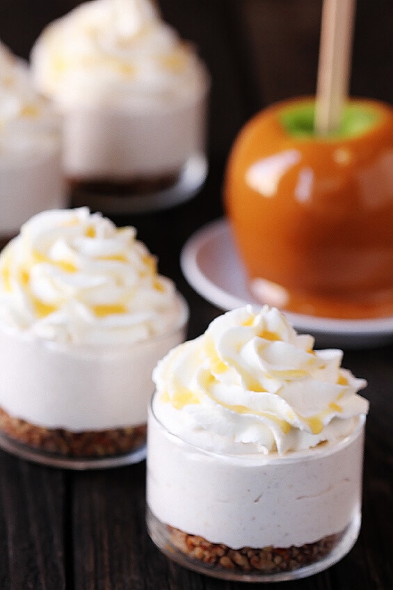 caramel apple cheesecake jars with whipped cream and caramel apple in the background
