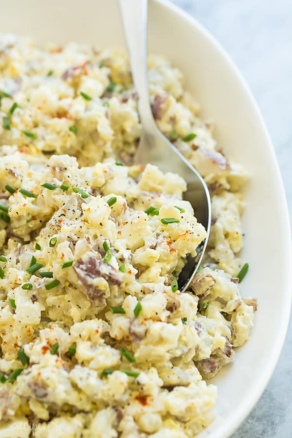 potato salad close up with spoon in white bowl