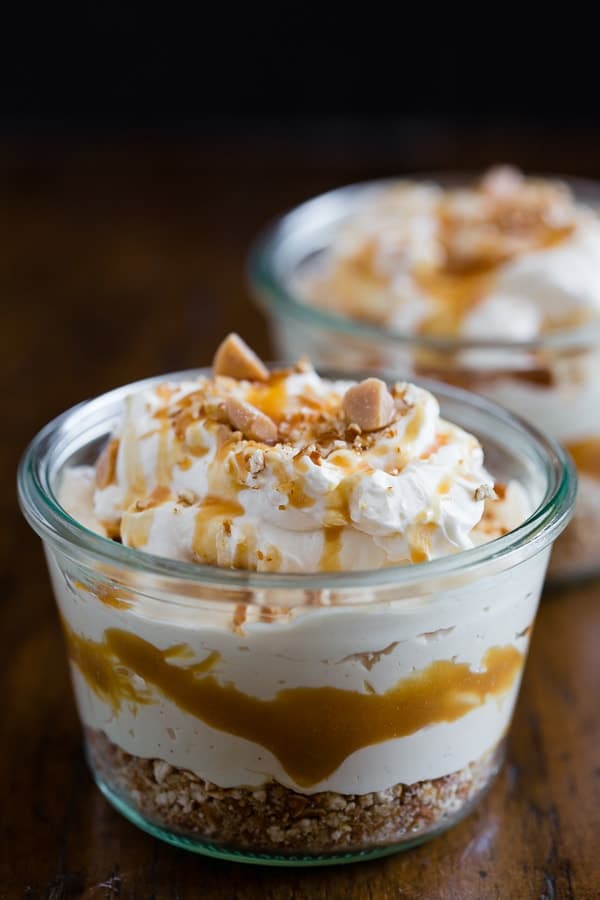 salted caramel no bake cheesecake jars with whipped cream and caramel drizzle on top